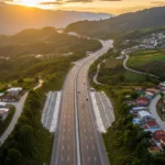 Fotografía aérea de una carretera moderna atravesando un paisaje montañoso y comunidades rurales en Guatemala.