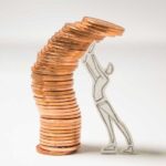 imagen de una persona hecha de papel sosteniendo monedas apiladas