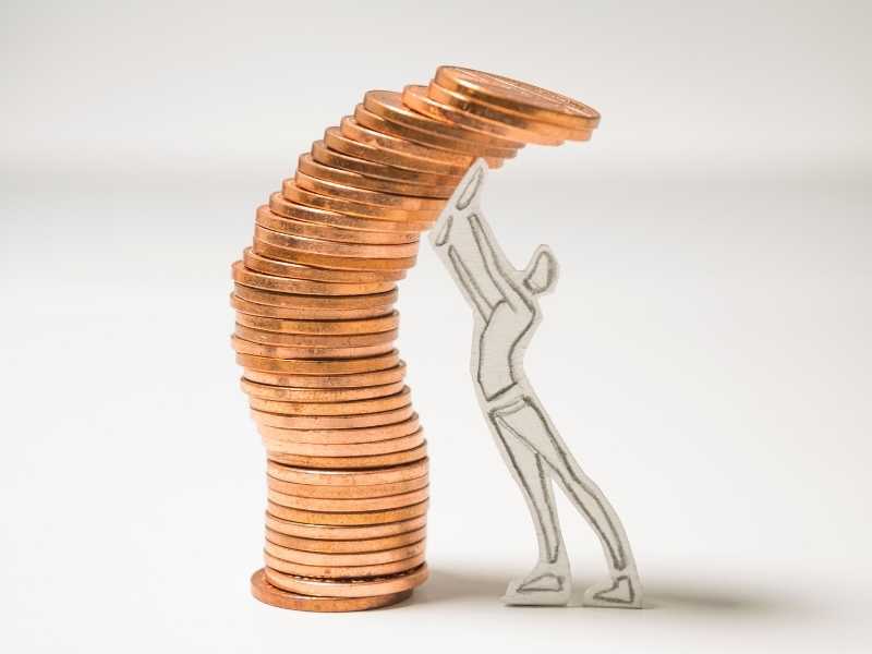 imagen de una persona hecha de papel sosteniendo monedas apiladas
