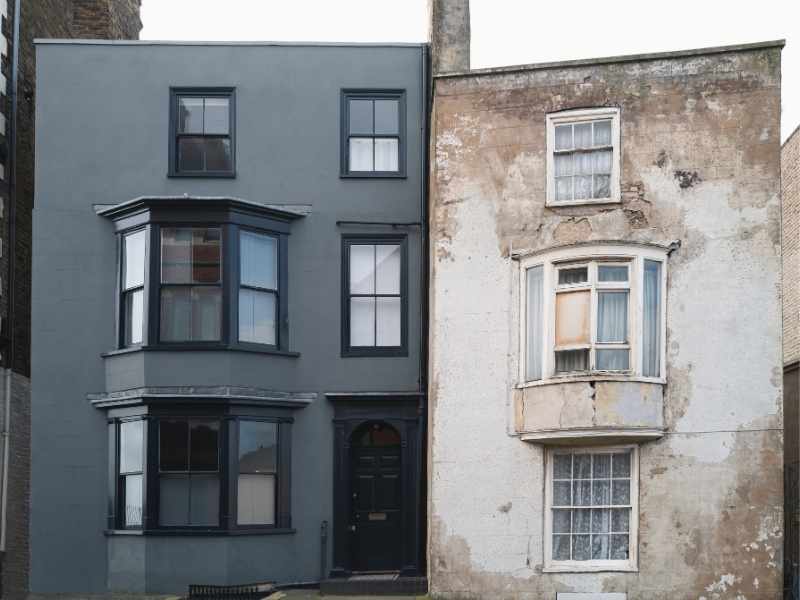 Comparativa visual de dos edificios colindantes: una fachada renovada frente a una original, ilustrando el proceso de gentrificación y cambio de perfil económico del barrio.