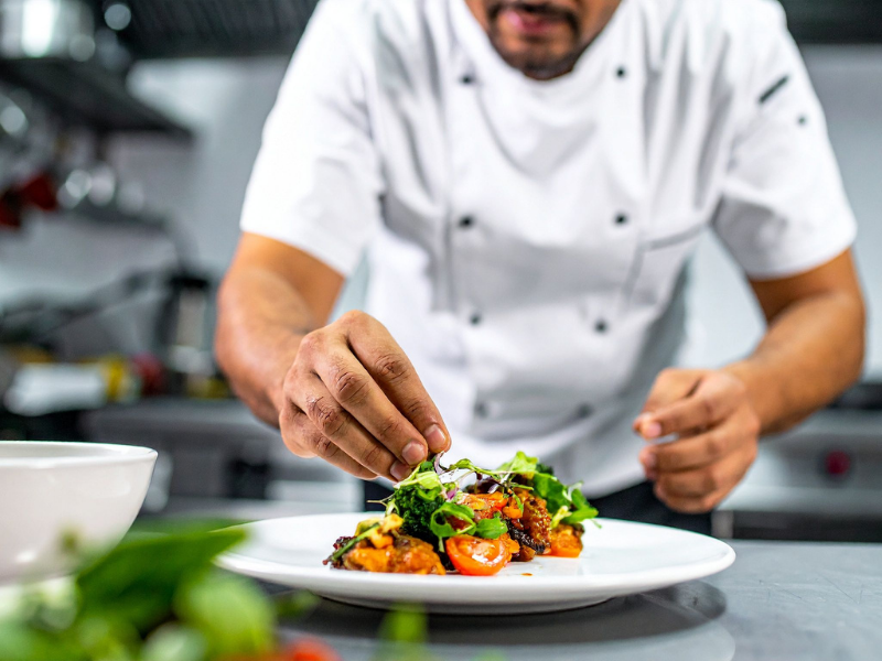Personal de cocina siguiendo un manual de procedimientos estandarizados, simbolizando la calidad consistente en una cadena de restaurantes en expansión.